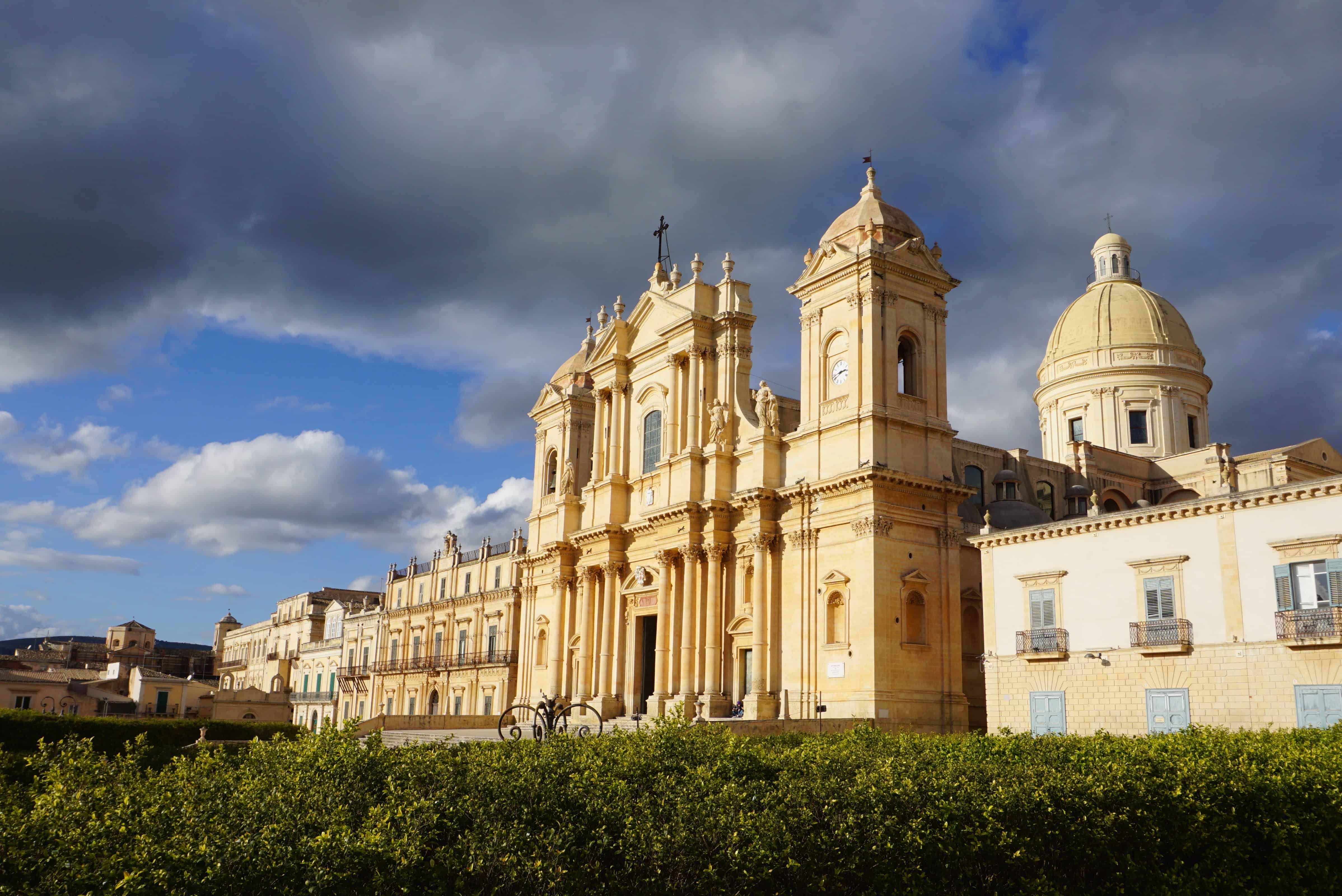 baroque building lit up in sunlight with dark clouds behind it