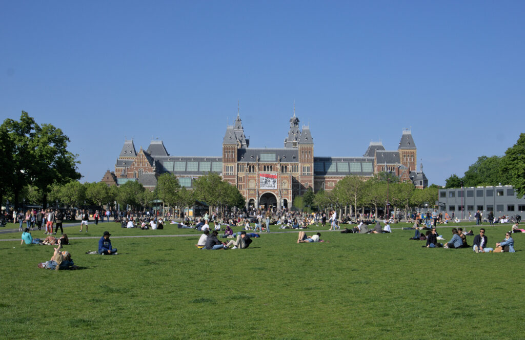 people relaxing on a green in front of Amsterdam's Rijksmuseum.