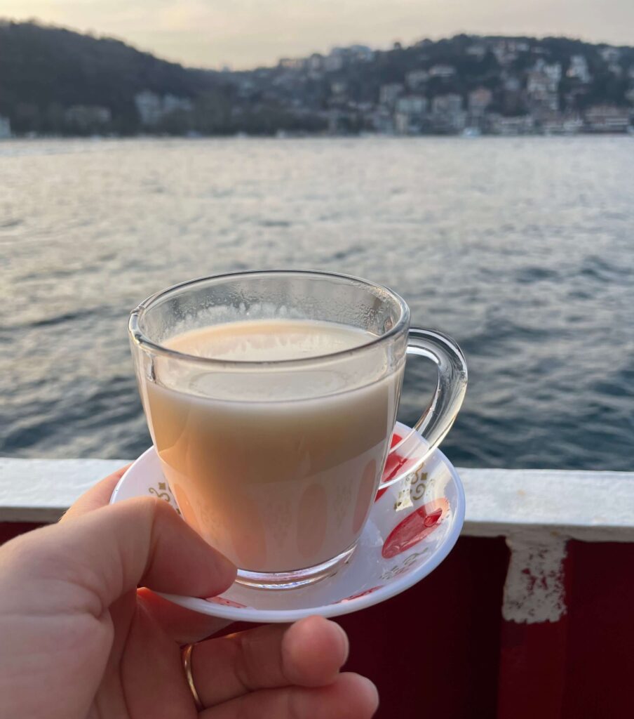 Glass of salep, a traditional Turkish beverage, with view of Istanbul and the Bosphorus in the background.