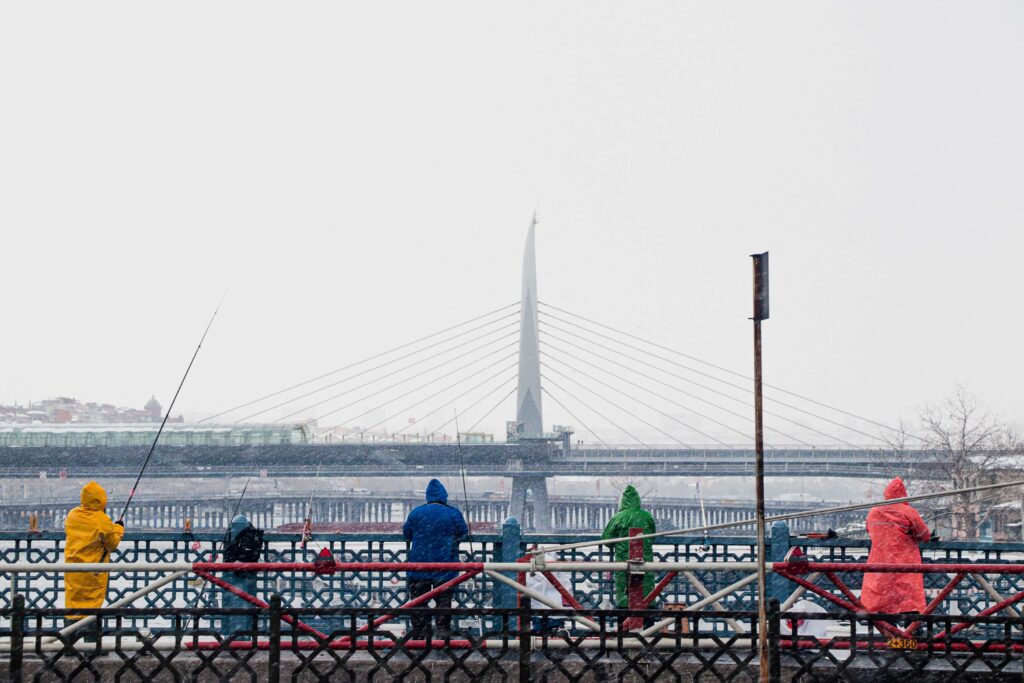 people fishing of a bridge in Istanbul while it snows.