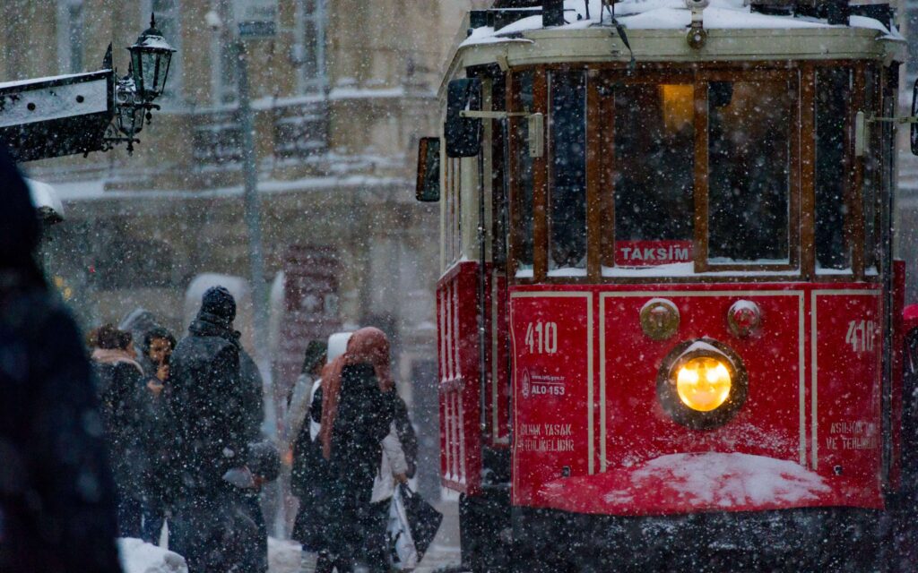 Red historic tram in Istanbul operating during a snowstorm.