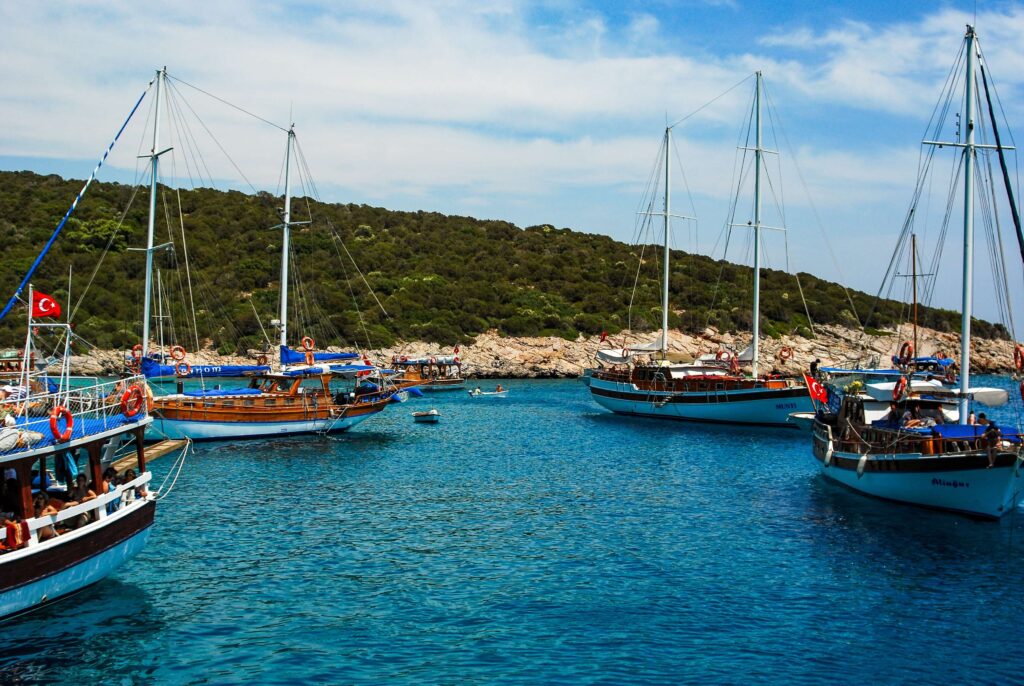 sail boats sitting in azure blue Mediterranean waters.