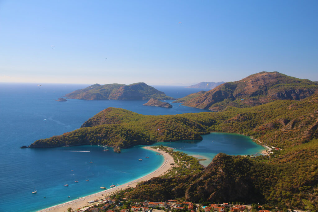 The blue lagoon of Fethiye as seen from above, surrounded by forest covered hills.