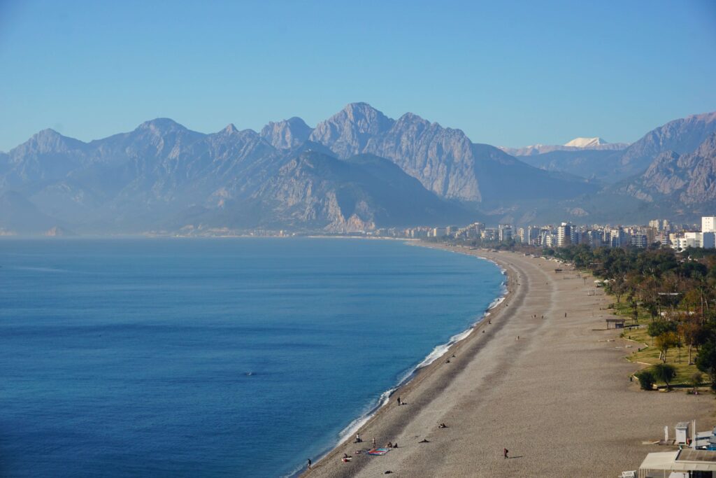 beach in antalya, one of the best places to go in turkey for families, with mountains in the background.