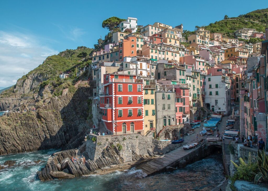 red and pink colorful buildings built into a cliff on the ocean.