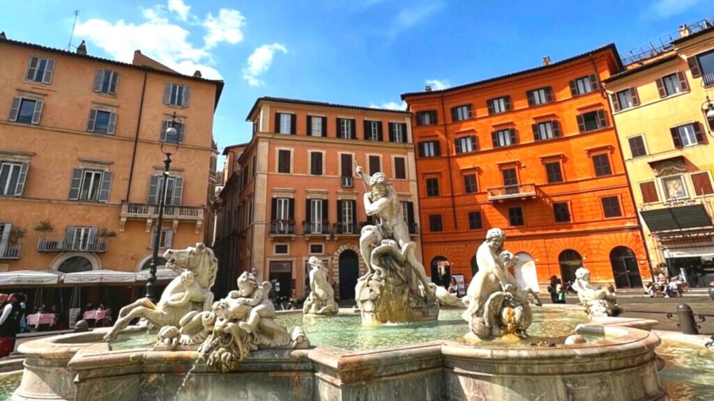 piazza navona fountain in Rome with colorful buildings behind it.