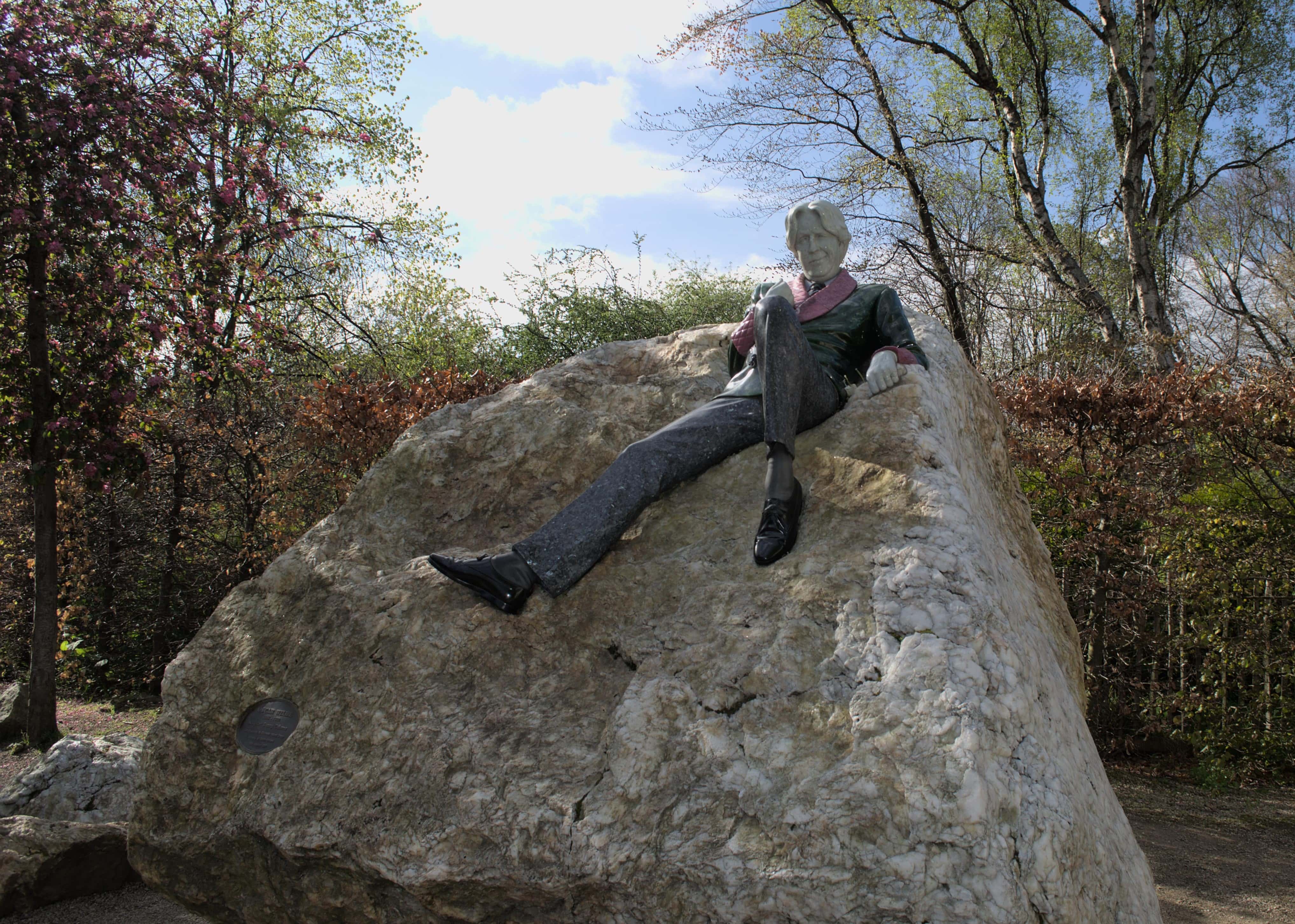 statues of Oscar Wilde reclining on a rock