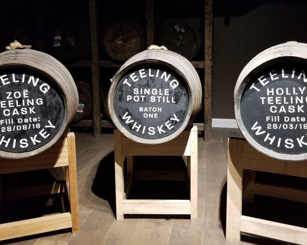 Three wooden whiskey barrels from Teeling, each with chalk-written labels, including 'ZOE Teeling Cask' and 'HOLLY Teeling Cask', exemplifying the storied craft encountered on the best whiskey tours in Dublin.