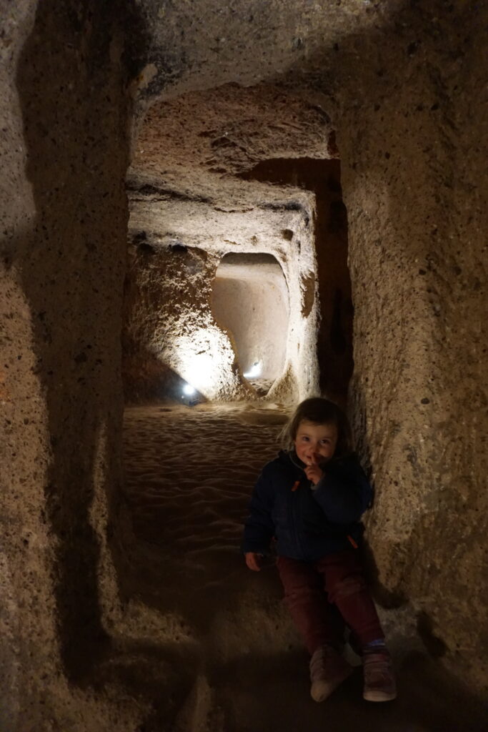 little girl sitting in a tunnel in Kaymakli underground city.