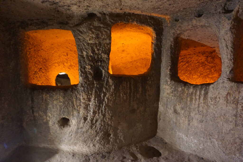 rooms cut into stone, illuminated with orange light, in the underground city of Kaymakli.