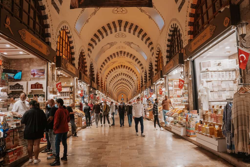 indoor market in turkey. Stalls line a central walkway with a domed roof. people shop and walk through the market.