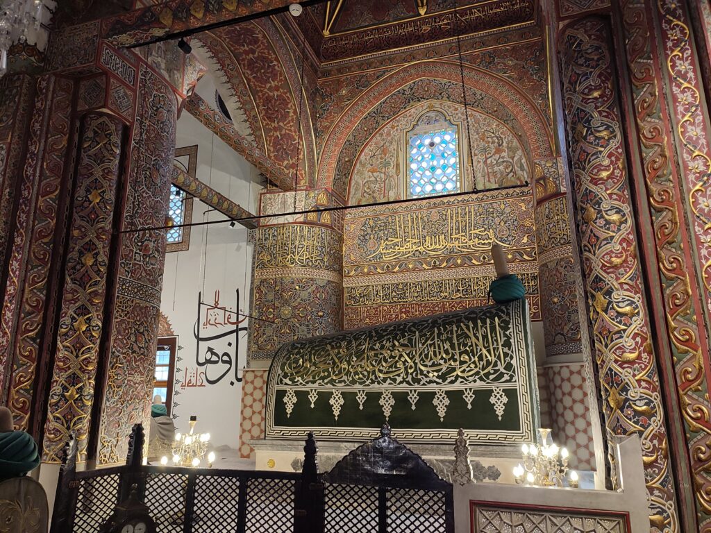 tomb of the famous Persian poet, Rumi, with gold gilded walls covered in intricate designs, including arabic caligraphy.