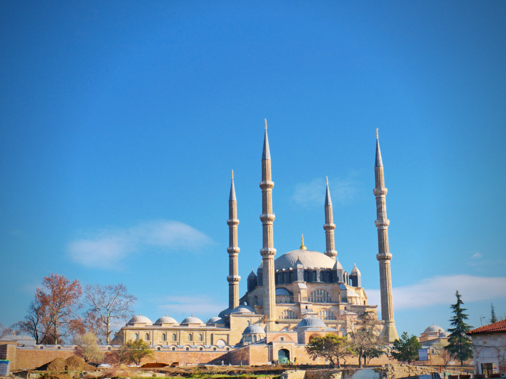 pinkish colored mosque with blue dome and four minarets.