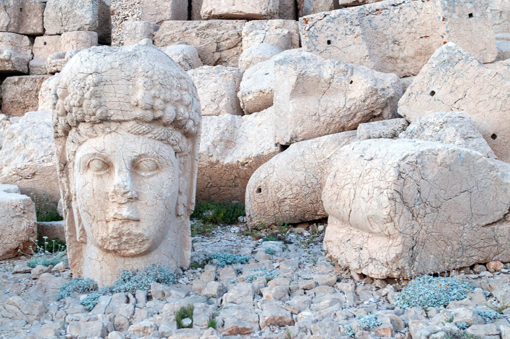 statue head sitting on the ground amidst rubble.