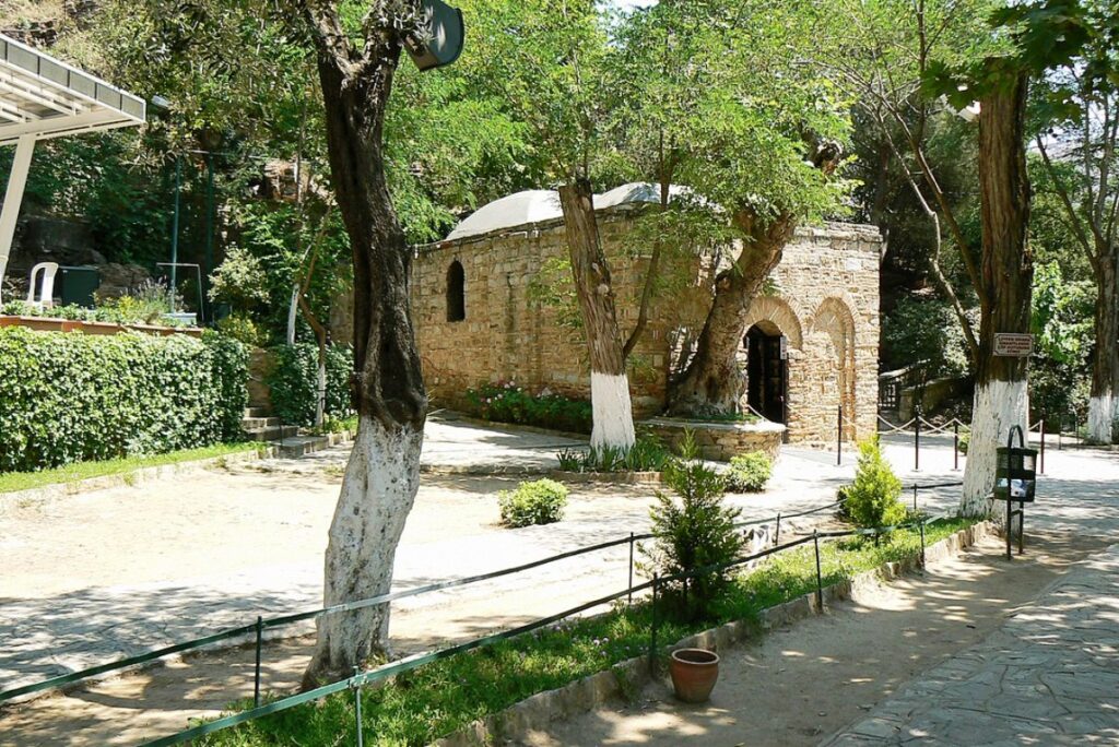 small stone house behind trees.