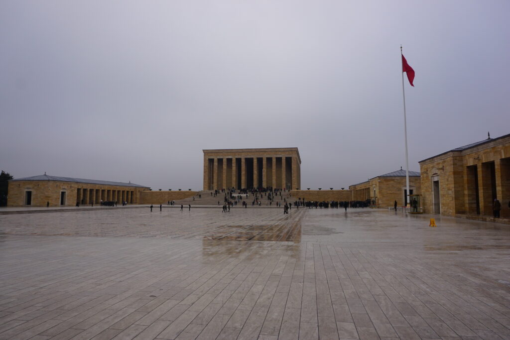 a mausoleum of orange stones with a stone courtyard in front of it.