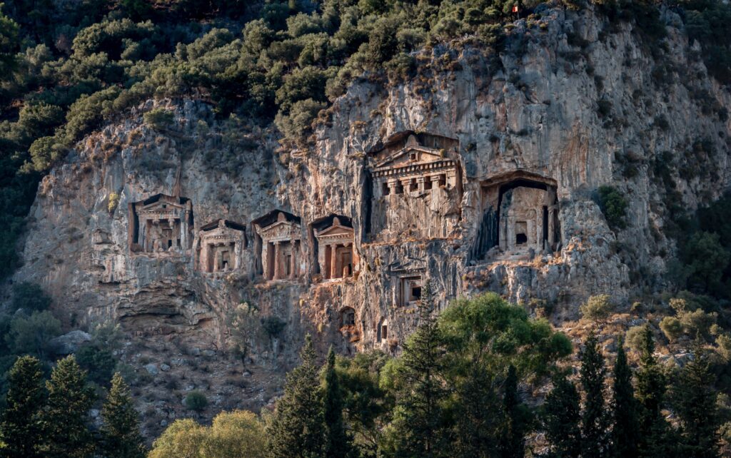 columned building facades carved directly into the rock face on a hillside.