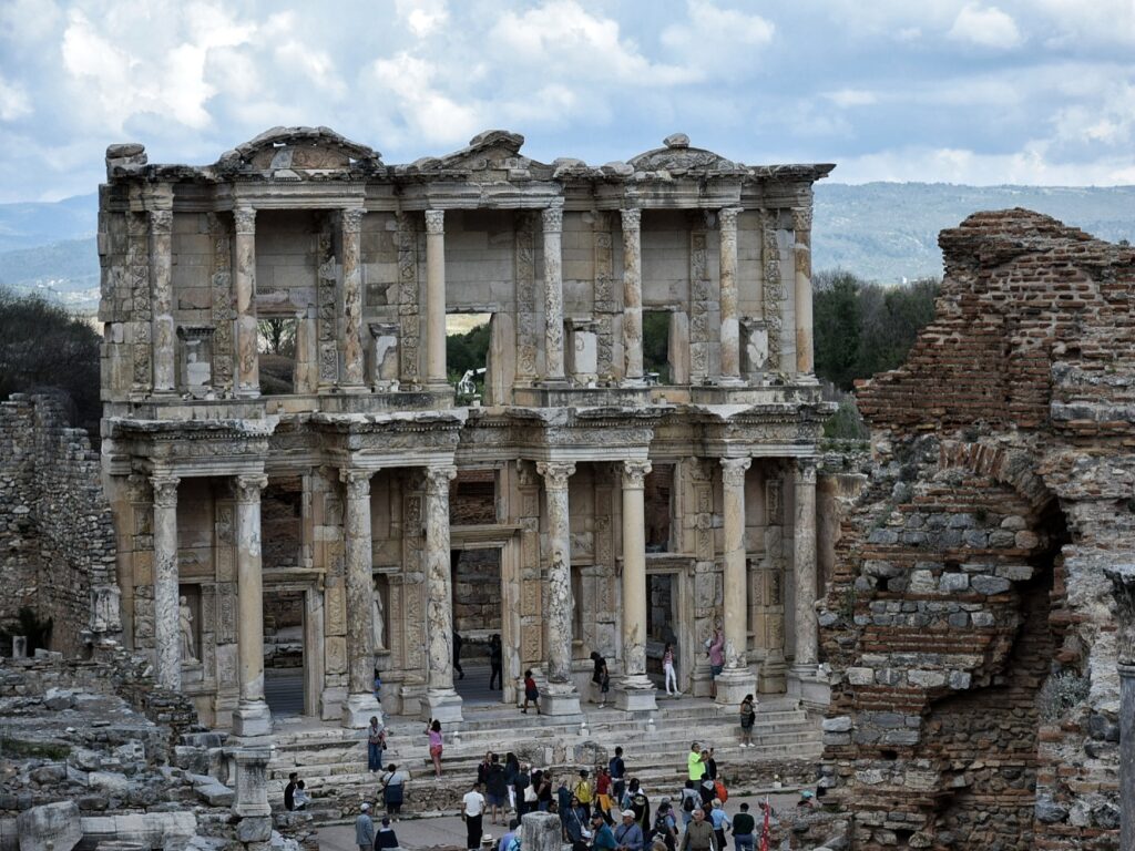 large facade of an ancient building with two levels of columns and windows.