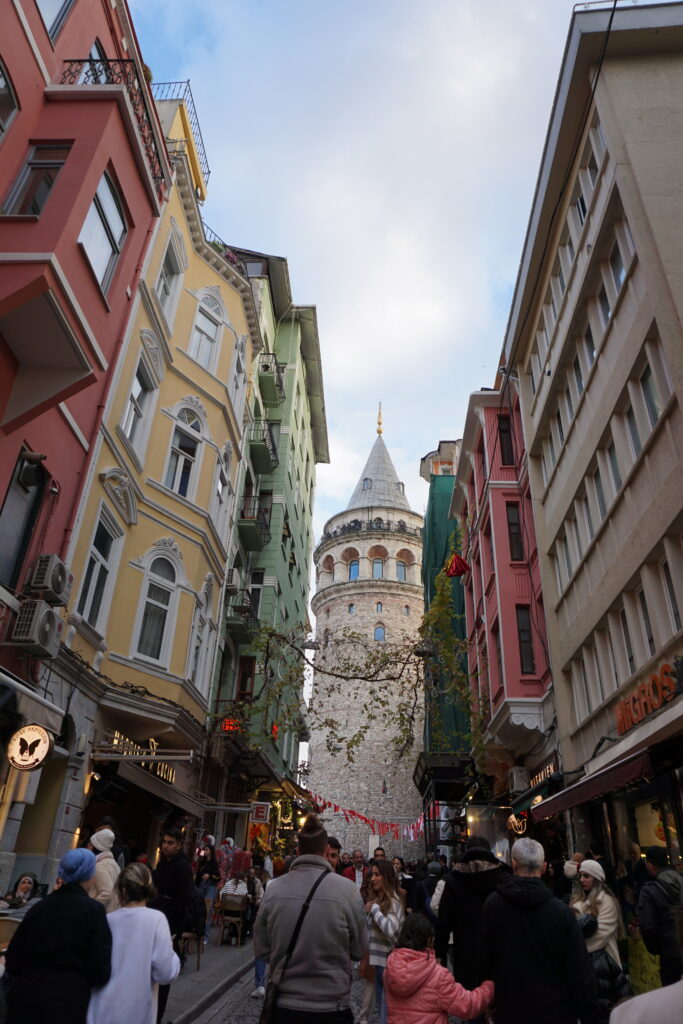 istanbul's galata tower with pointed top peeking through a gap in colorful buildings