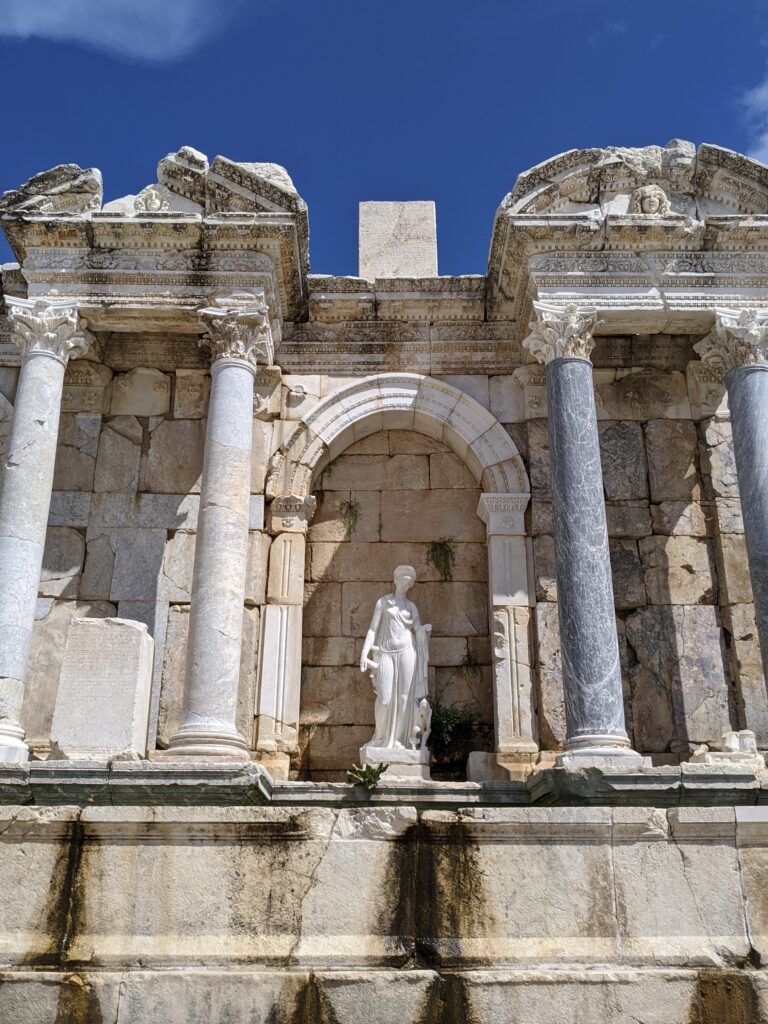 marble statue of woman in roman dress aurrounded by marble columns in ancient ruins of Sagalassos.