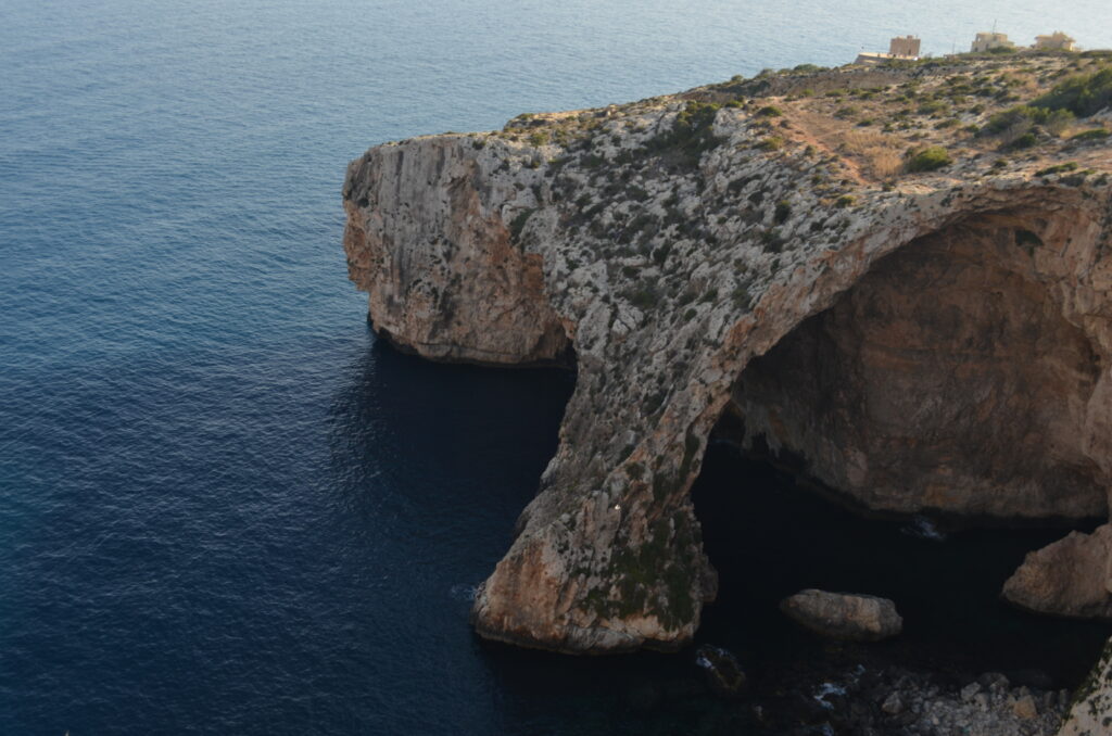 a sea cave, photographed from above, formed by a natural rock bridge on the west coast of Malta.