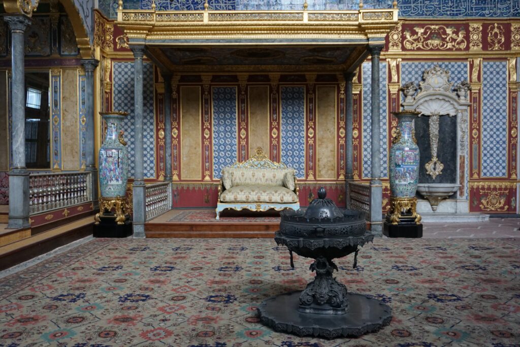 opulent room with lounge, decorated walls and carpets, and fireplace inside an ottoman palace.