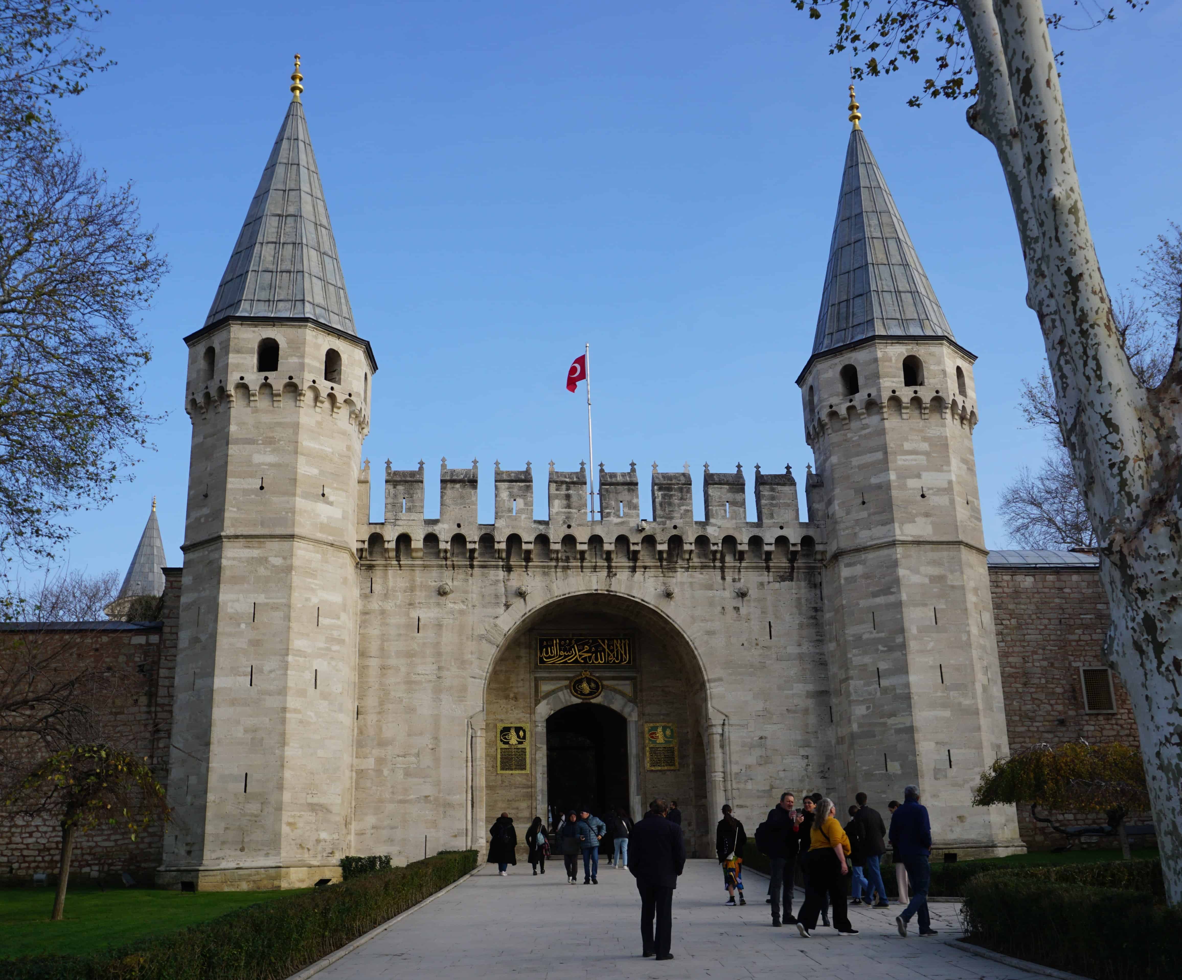 palace entrance with gate in the center and two pointed towers on either side.