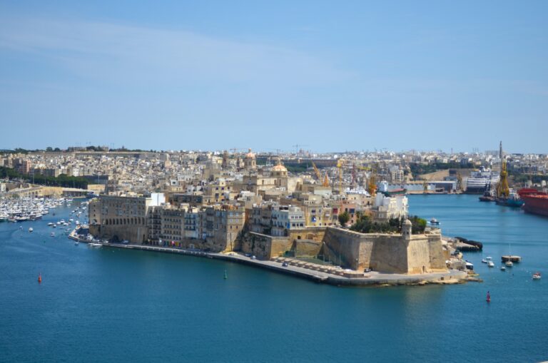 view of medieval stone walled city along blue harbor