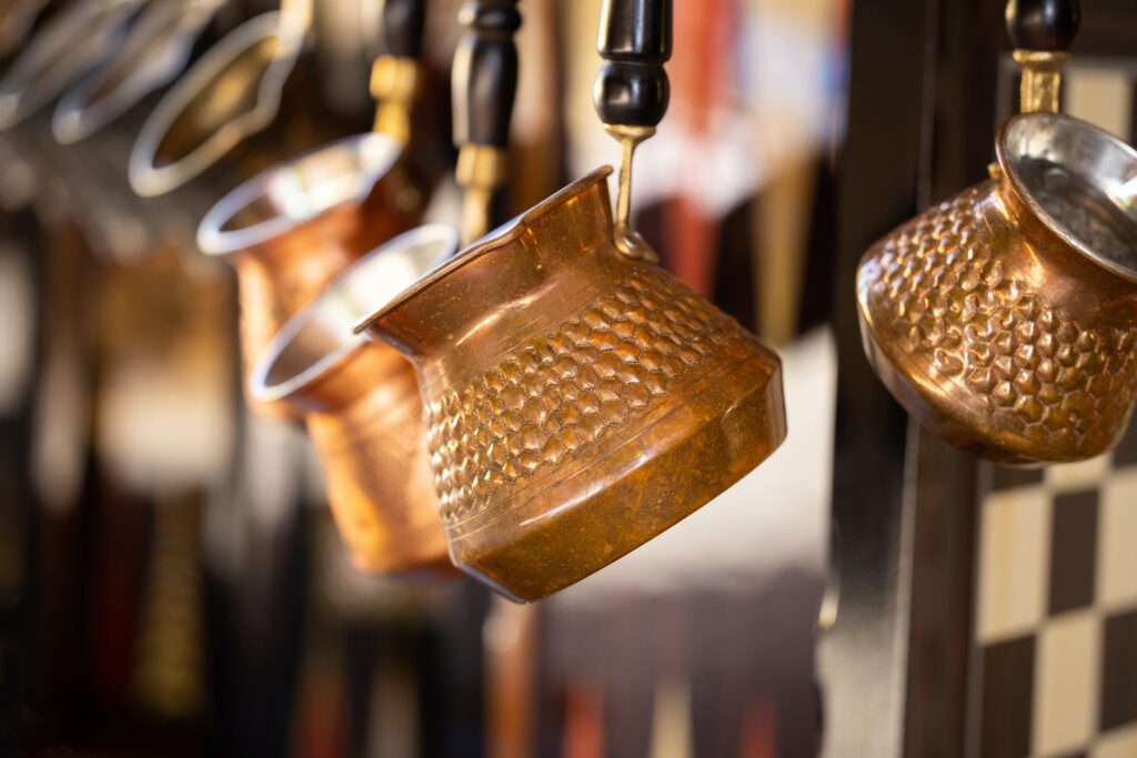 Copper cezve pots hanging on display at a store.