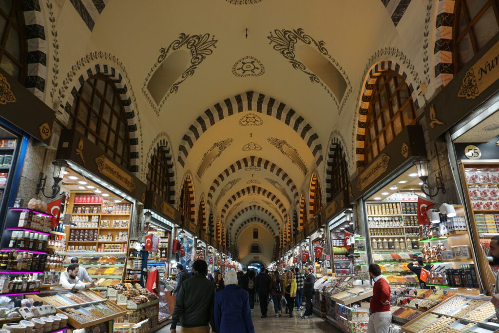 inside a market in Istanbul, with a high arches ceiling decorated with Ottoman design work and stalls lining the walls