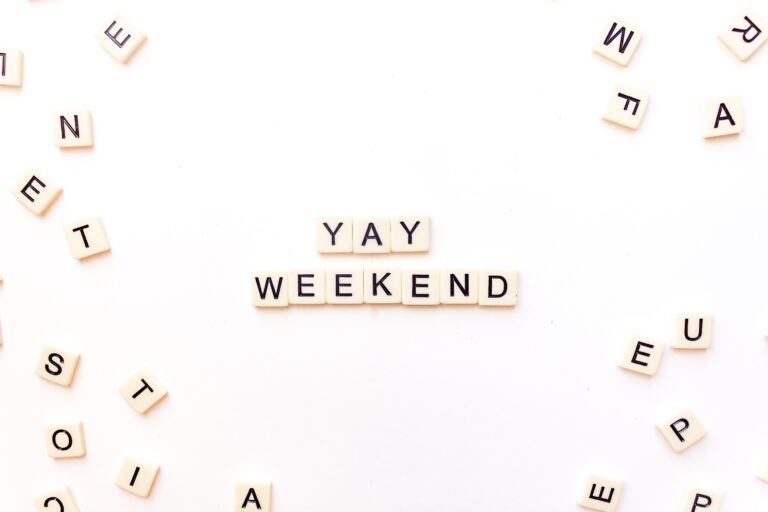 Scrabble tiles on a white surface spelling out 'YAY WEEKEND' surrounded by scattered letters, conveying excitement for the weekend.