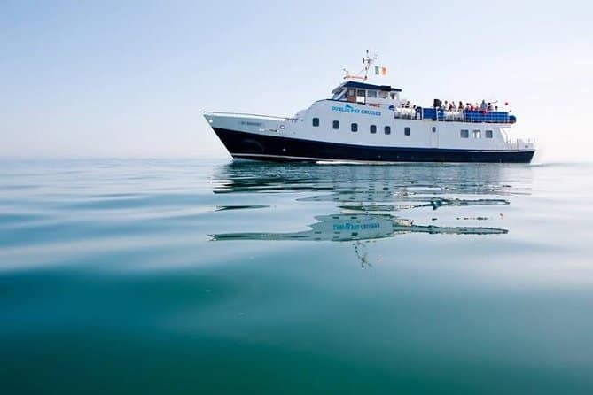 The 'Dublin Bay Cruises' boat serenely floats on glass-like water, reflecting its name and form, a prime choice for the best boat Dublin boat tour, under a clear sky.