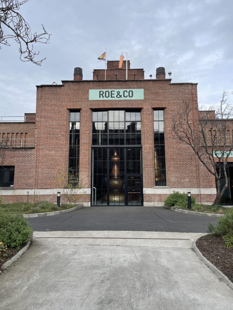 The entrance to Roe & Co Distillery with a large glass door and brick facade, an inviting start to a top-rated whiskey tour in Dublin.