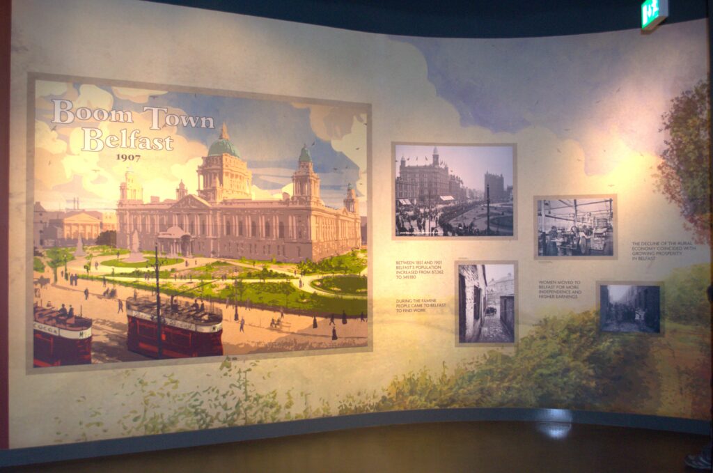 Exhibit wall titled "Boom Town Belfast 1907," featuring an illustration of Belfast City Hall and historical photos, capturing urban growth and industry.
