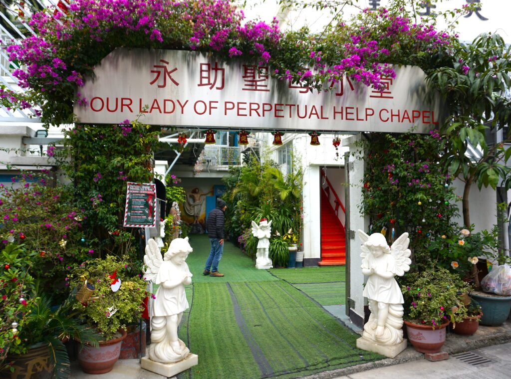 Our Lady of Perpetual Help Chapel entrance in Tai O fishing village. Angel statues, flowers, and greenery adorn the chapel. Religious site.