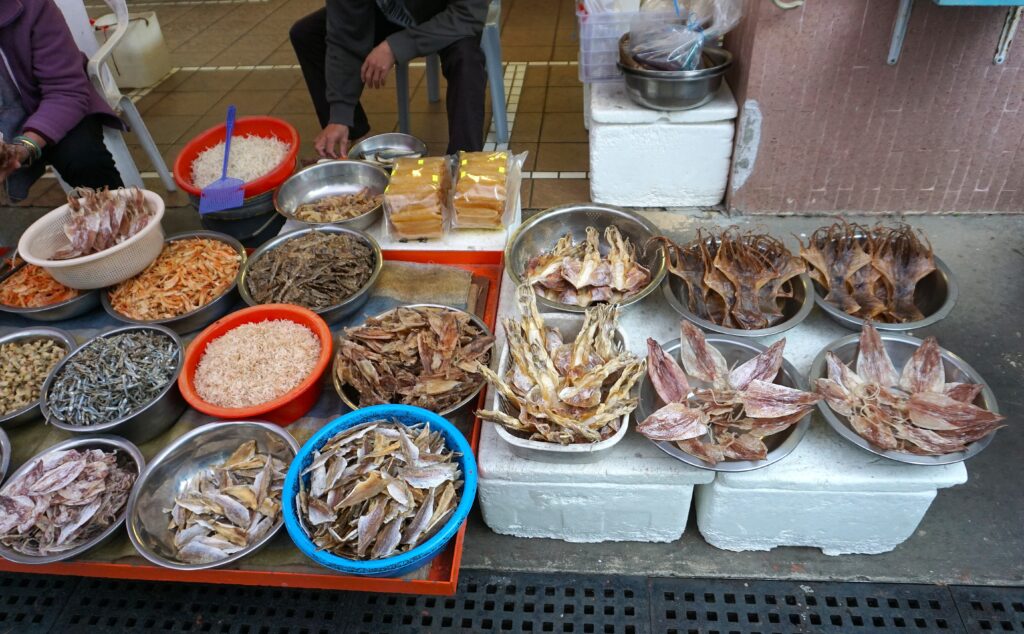 Dried seafood market stall. Bowls of dried fish, squid, and shrimp on display. Asian food market.
